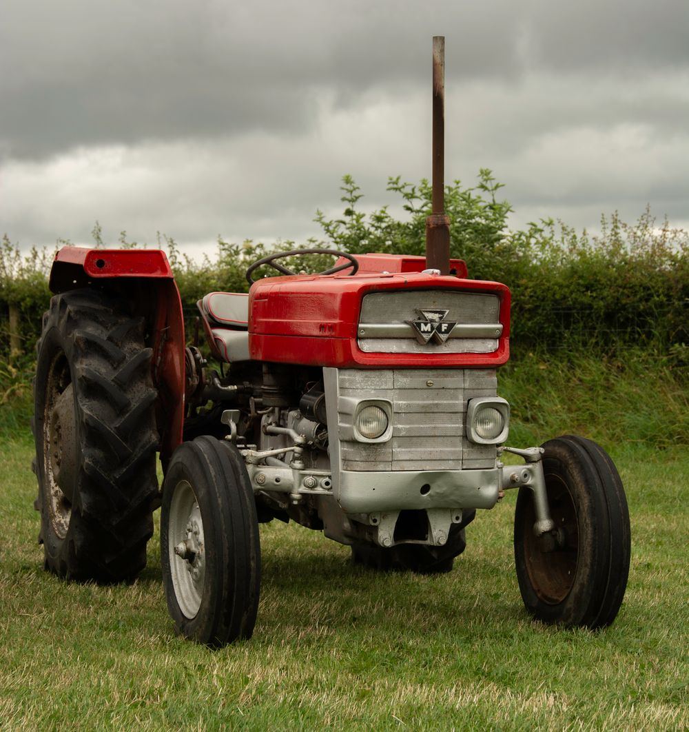 A classic red tractor parked in a grassy field
